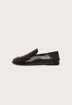 Mocassin en cuir noir avec petit talon, bout arrondi et surpiqûres, présenté de profil sur un fond blanc uni.