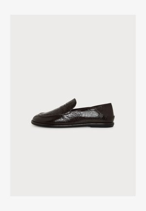 Mocassin en cuir noir avec petit talon, bout arrondi et surpiqûres, présenté de profil sur un fond blanc uni.