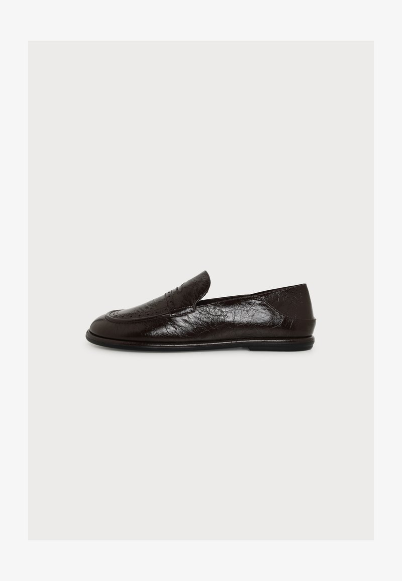 Mocassin en cuir noir avec petit talon, bout arrondi et surpiqûres, présenté de profil sur un fond blanc uni.