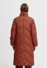 Rote Pufferjacke mit Chevron-Muster, hohem Kragen und langen Ärmeln. Die glatte Textur und die minimalen Hardware-Details betonen das Design.