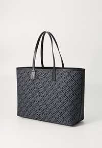 Black tote bag with geometric pattern in dark blue and gray, smooth leather handles, and structured design. Lightweight and spacious.