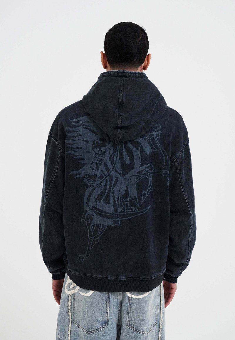Zwarte denim hoodie met een grote grijze grafische ontwerpen op de achterkant, met een figuur en ingewikkelde details. Ribbelboorden en zoom.