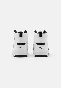 Baskets montantes blanches avec accents noirs, cuir texturé, col rembourré et tirette au dos. Présente le logo Puma sur le talon.