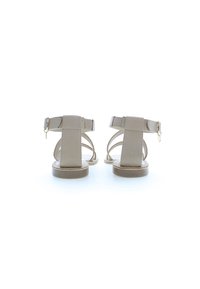 Beiga sandaler med platt sula, flera remmar och en justerbar ankelspänne. Slät yta med minimalistisk design och inga mönster.