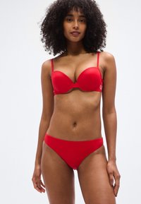 Σετ κόκκινου μπικίνι με επενδεδυμένο σουτιέν με ρυθμιζόμενες τιράντες και αντίστοιχο σλιπ χαμηλής μέσης, κατασκευασμένο από απαλό, ελαστικό ύφασμα.