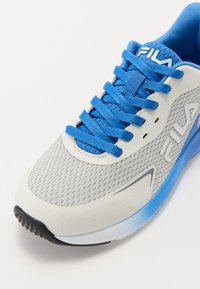 Chaussure de course pour homme en gris avec tige en mesh, lacets bleus et semelle en caoutchouc. Présente un logo blanc et une semelle extérieure dégradée bleue.