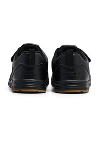 Zwarte sportieve schoenen met een gladde synthetische bovenkant, afgeronde hak en rubberen zool. Voorzien van een klittenbandsluiting en een reliëflogo op de hak.