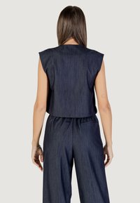 Top corto blu navy senza maniche, con una texture liscia e sottili righe verticali. Pantaloni abbinati a gamba larga con vita elastica.