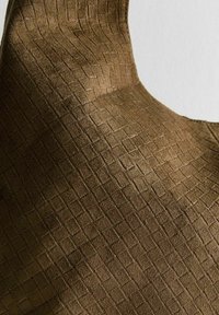 Primo piano di un tessuto in suede marrone con un sottile motivo a griglia in rilievo che mostra texture e curvature.