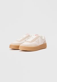 Sneakers bianchi con sovrastruttura in suede beige, suola in gomma e dettagli del logo sul lato. Presentano un classico design con lacci e colletto imbottito.