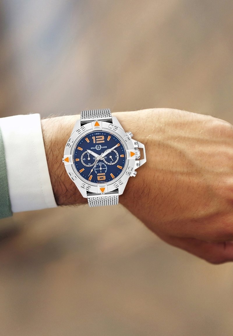 Silberner Chronograph mit blauem Ziffernblatt, orangefarbenen Akzenten und einem Mesh-Armband. Verfügt über Ziffern bei 12 und 6 sowie Hilfszifferblätter zur Zeitmessung.
