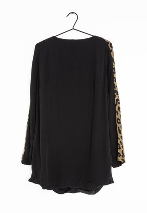Chemise noire à manches longues sur un cintre avec des panneaux à motif léopard courant sur les côtés extérieurs des deux manches.