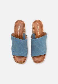 Infradito in denim blu con suola in pelle marrone. Presentano un'apertura sulla punta e ampie fibbie incrociate. La taglia 37 è visibile all'interno.
