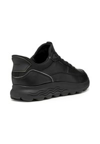 Las zapatillas negras presentan un upper de cuero suave, punta redonda y una suela de goma texturizada con patrones en forma de ola. Logotipo de Geox en el costado.