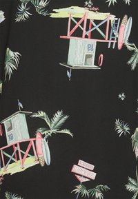 Tkanina z wzorem przedstawiającym kolorowe domki surfingowe z numerami, liśćmi palmy oraz znak "Rancho Motel" na czarnym tle.