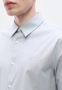Ριγέ πουκάμισο με κουμπιά σε ανοιχτό μπλε και λευκό, με μυτερό γιακά, διακριτική κεντημένη λογότυπο και απαλό βαμβακερό ύφασμα.