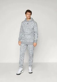Sivá mikina s vzorom a zodpovedajúce nohavice z mäkkého materiálu, s klokannou kapsou, elastickými manžetami a logom na hrudi.