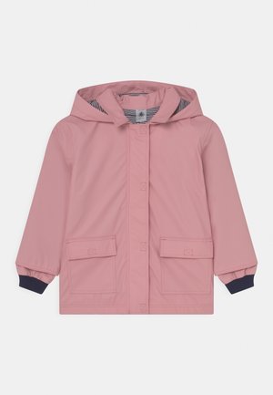 Chaqueta impermeable rosa con capucha, dos bolsillos delanteros, puños de las mangas en azul marino y forro interior a rayas. Textura suave, diseño casual.