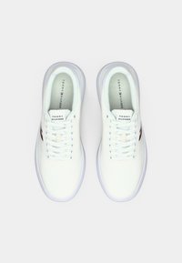 Witte sneakers met een gestructureerde bovenkant, ronde neus en gevoerde kraag. Voorzien van lichtblauwe veters en rode en blauwe accenten aan de zijkant.