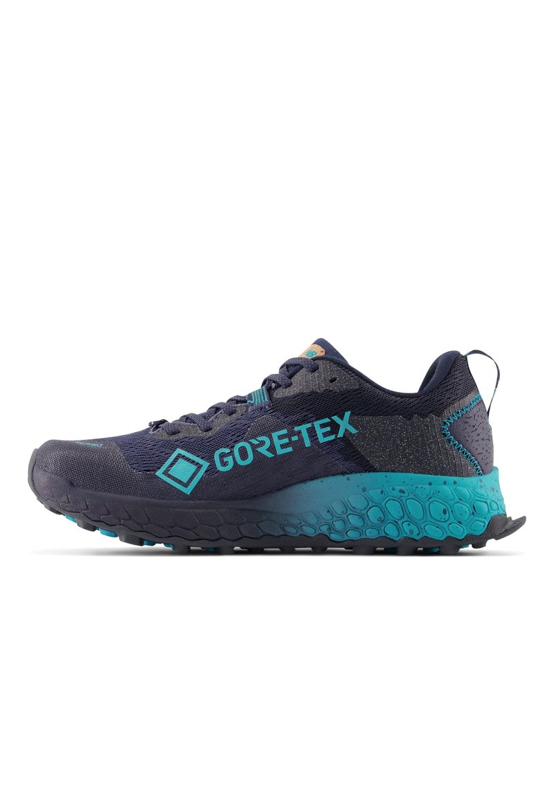 Zapatillas de trail running en azul marino oscuro con acentos turquesa. Están hechas de materiales de malla y sintéticos, y cuentan con una suela texturizada para mayor agarre.