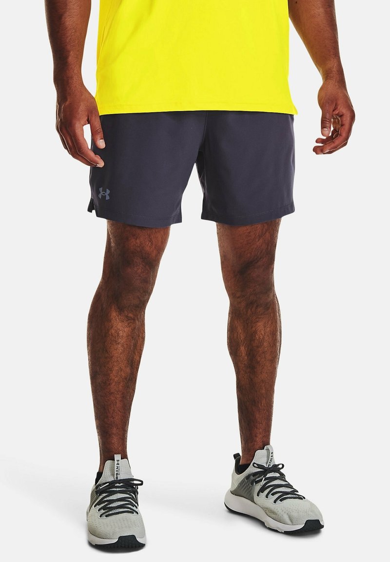 Tmavě šedé šortky vyrobené z lehkého materiálu, s plochým pásem, bočními rozparky a logem Under Armour na lemu. Ladící šedé tenisky.