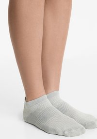 Ljust grå ankelsockor gjorda av ett texturerat stickat material. Har en ribbad mudd och en förstärkt tå för hållbarhet.