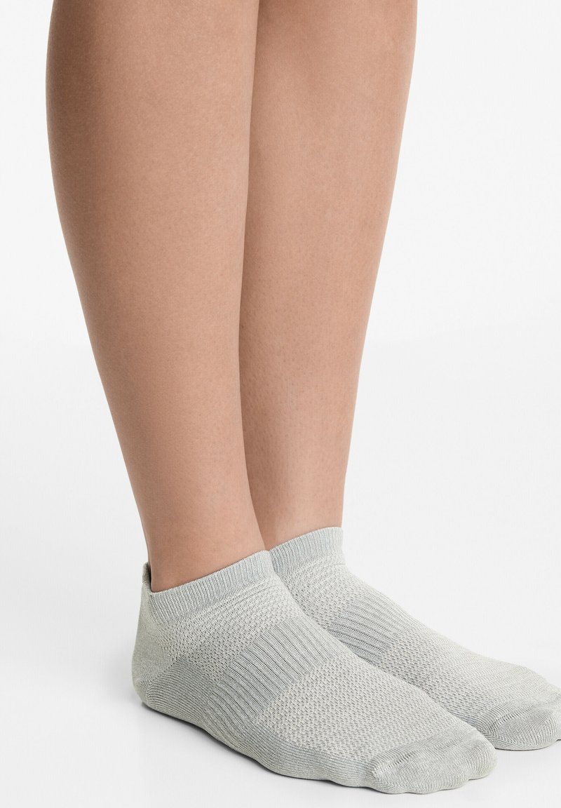 Ljust grå ankelsockor gjorda av ett texturerat stickat material. Har en ribbad mudd och en förstärkt tå för hållbarhet.