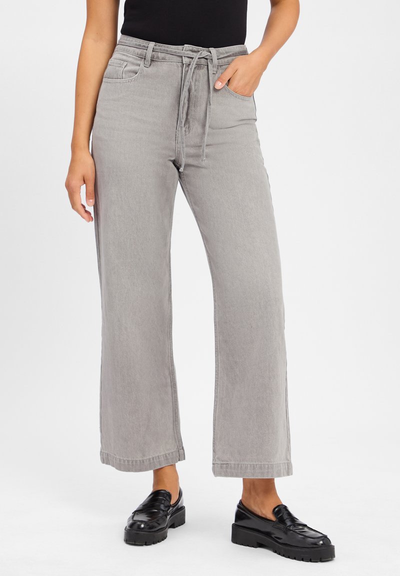 Szare szerokie spodnie o kroju dzwonów wykonane z denimu, z elastycznym paskiem w talii oraz dwiema bocznymi kieszeniami, z prostą, skróconą nogawką.