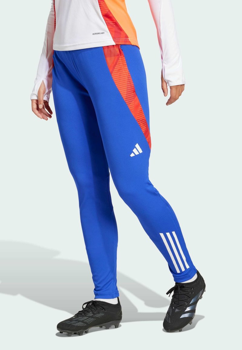 Blaue Sportleggings mit einem roten diagonalen Streifen, aus glattem Material hergestellt; verfügen über drei weiße Streifen am Unterschenkel und ein enganliegendes Design.
