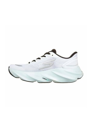 Chaussure de sport blanche avec une semelle épaisse sculptée, des lacets noirs et un logo argenté sur le côté, conçue pour le soutien de la voûte plantaire et le confort.