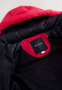 Schwarze Fleecejacke mit rotem Innenfutter der Kapuze. Enthält Logo und Etikett innen. Glatte Oberfläche mit gepolsterter Gestaltung, kombiniert Wärme und Stil.
