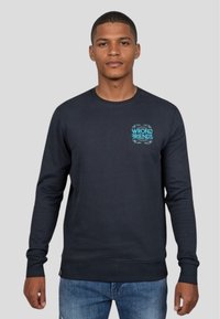 Mörkblå sweatshirt med långa ärmar, med en ljusblå "WRONG FRIENDS" grafik på bröstet, ribbade muddar och en klassisk rund halsringning.