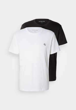 Two crew neck t-shirts, one white and one black, made of cotton. Each features a small CK logo on the left chest, short sleeves, and a regular fit.