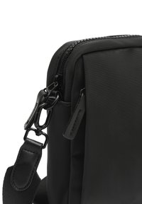 Borsa a tracolla nera in nylon con una texture liscia, dotata di chiusura con zip, accessori in metallo e tracolla regolabile. Design compatto per un facile trasporto.