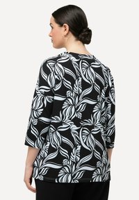 Černobílý dlouhý rukáv top s květinovým vzorem a plynoucími listy, vyrobený z měkké tkaniny. Kulatý výstřih a volný střih.