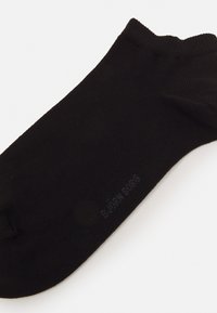 Schwarze Knöchelsocke aus glattem Stoff; mit einem gerippten Bund und einem dezenten Logo, das an der Seite aufgedruckt ist. Einfaches, zurückhaltendes Design ohne Muster.