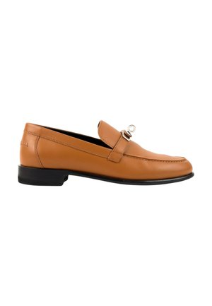 Lichtbruine leren heren loafer met zwarte zool en zilverkleurige metalen gesp op witte achtergrond.