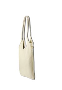 Beige leren tote bag met twee lange handvatten, een naadloos zijdesign en een kleine ronde hardware detail nabij de bevestiging van het handvat.