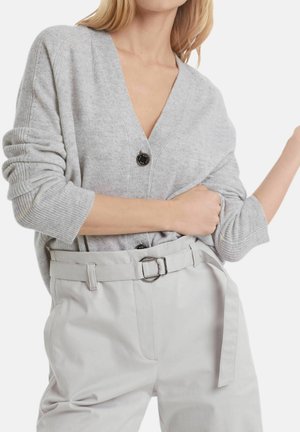 Cardigan gris en maille avec un col en V profond, orné d'un bouton noir. Associé à un pantalon taille haute gris clair et une taille ceinturée.