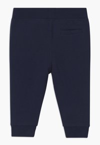 Pantalones de chándal azul marino en una suave mezcla de algodón, con una cinturilla ajustada, tobillos acampanados y un pequeño bolsillo trasero.
