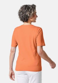Korte mouwen, ronde hals oranje T-shirt van zachte katoen, met een getailleerde silhouet en een gladde textuur. Achteraanzicht toont een eenvoudig ontwerp.