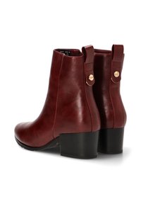 Botas de tobillo de cuero burdeos con una textura suave, punta redonda y tacón cuadrado. Presentan detalles de hardware dorado en la parte posterior.