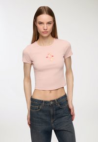 Maglietta corta rosa chiaro in cotone morbido, con una grafica di un coniglio e cuori. Maniche corte e scollatura rotonda.