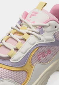 Gros plan sur une basket FILA rose, jaune, blanche et lavande avec tissu en maille, lacets blancs et logo de la marque sur le côté et la languette.