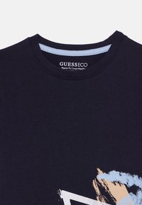 Μπλε βαμβακερό μπλουζάκι με στρογγυλή λαιμόκοψη, με αφηρημένο σχέδιο σε μπλε και μπεζ. Κανονική εφαρμογή με λεπτομέρεια λαιμόκοψης σε ανοιχτό μπλε χρώμα.