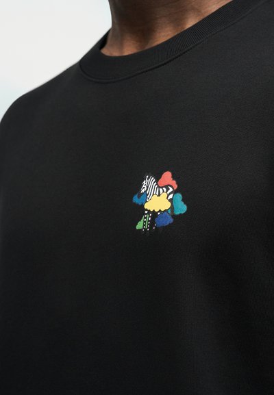 Μαύρο πουκάμισο με μικρό πολύχρωμο γραφικό ενός ζέβρα που περιβάλλεται από πολύχρωμα σχήματα σύννεφων στο στήθος.