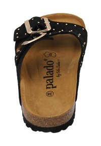 Sandal in suede nera con suola in sughero, caratterizzata da una fibbia decorativa e dettagli borchiati. L'interno presenta una superficie tan e testurizzata con logo.