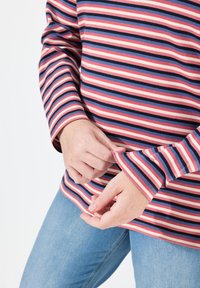Chemise à manches longues rayée en rose, rouge, bleu et marine avec une coupe décontractée. Le tissu a une texture lisse, mettant en valeur des rayures horizontales contrastées.