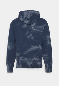 Tmavě modrá batikovaná mikina s texturovanou látkou, dlouhými rukávy a kapucí se stahovací šňůrkou. Má klokánovou kapsu a žebrované manžety.