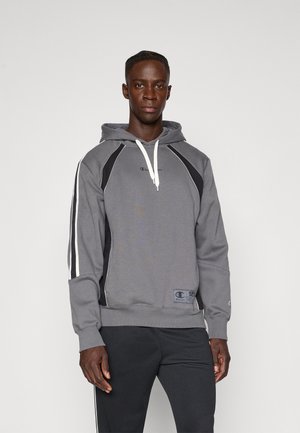 Hanorac gri cu glugă, cu accente negre, șnur alb și dungi laterale. Prezintă un logo pe piept și un material texturat.